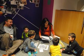 Frau erklärt vier Kindern die Spielregeln.