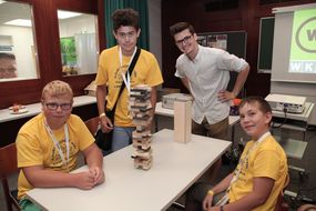 Drei Buben und ein Mann haben einen Turm aus Holzbausteinen gebaut