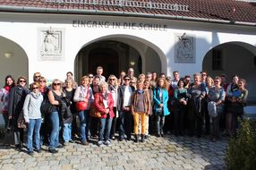Die Teilnehmerinnen und Teilnehmer lachen vor der Kulisse der Volksschule Mauerbach in die Kamera