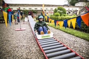 Bub fährt beim NÖ Familienfest auf der Schallaburg mit einer Kiste eine Rollbahn hinunter