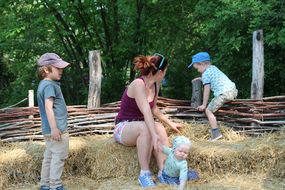 Drei Kinder und eine Frau sitzen beim Familienfest Donau-Auen auf Stroh