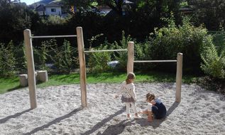 Zwei Kinder spielen vor einem Klettergerüst.