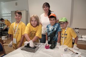 Vier Buben und eine Frau experimentieren zusammen bei der 3. Kinder Business Week