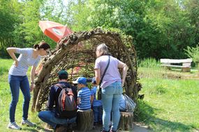 Besucher bestaunen Unterschlupf aus Ästen beim Familienfest Donau-Auen