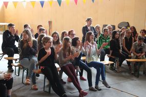 Kinder der Spielforscher-Werkstatt in der Europa-Mittelschule Prinzersdorf sitzen auf Bänken und klatschen.
