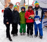 Fünf Personen mit Skihelmen und Hauben lachen in die Kamera.
