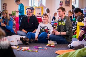 Spielbegeisterte sitzen am Boden und lachen in die Kamera
