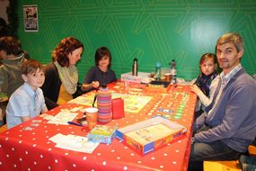 Begeisterte Familie spielt am Tisch ein Brettspiel.