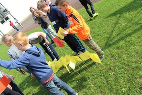 Kinder stecken gelbe Fahnen in die Wiese bei der Spielforscher-Werkstatt in der Europa-Mittelschule Prinzersdorf