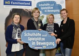Landesrätin Schwarz hält beim Seminar "Schul(t)räume" mit drei weiteren Damen ein Schild mit der Aufschrift "Schulhöfe und Spielplätze in Bewegung" in die Kamera.