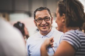 Ein Mann mit Brille lacht beim Sommerausklang an der Donau-Universtität Krems in die Kamera