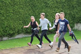 Zwei Mädchen und zwei Buben laufen Hand in Hand in einer Viererkette bei der Spielforscher-Werkstatt in der Europa-Mittelschule Prinzersdorf.
