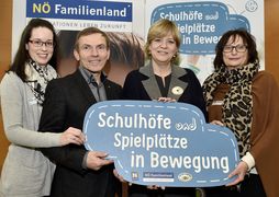 Vier lachende Gesichter und ein Schild mit "Schulhöfe und Spielplätze in Bewegung"