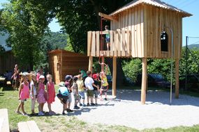 Kinder begutachten das große, hölzerne Kletterhaus.