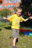 Ein Bub in einem gelben T-Shirt springt Springschnur.
