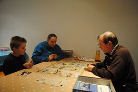 Ein Mann, eine Frau und ein Bub spielen konzentriert ein Spiel.