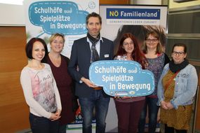Fünf Frauen und ein Mann halten beim Seminar "Schul(t)räume" ein Schild mit "Schulhöfe und Spielplätze in Bewegung" in die Kamera.