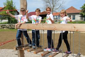 Kinder stehen auf einer Balancier-Brücke aus Holz.