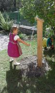 Ein Mädchen lässt bei einem Brunnen auf einem Spielplatz Wasser herunter.