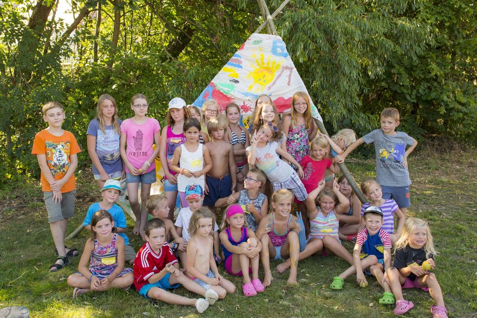 Kinder sitzen im selbst bemalten und selbst aufgestellten Tipizelt
