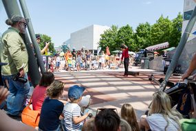 Teilnehmerinnen und Teilnehmer des Straßenfests sehen gespannt einem Künstler zu