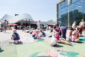 Kinder und Eltern sitzen am Boden und füllen Zettel aus