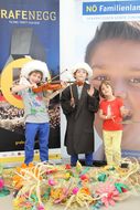 Drei Kinder probieren Instrumente aus und lächeln in die Kamera
