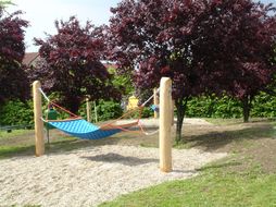 Blaue Hängematten bei einem Spielplatz.
