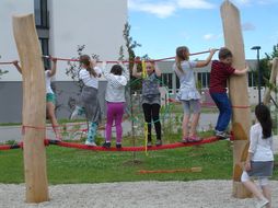 Kinder klettern zusammen auf einem großen roten Seil.