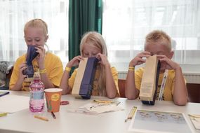 Drei Kinder riechen an Säckchen voll getrocknetem Tee.