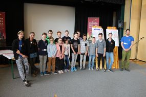 Einige Teilnehmerinnen und Teilnehmer der Spielforscher-Werkstatt in der Europa-Mittelschule Prinzersdorf stehen vor den zuvor gestalteten Plakaten.