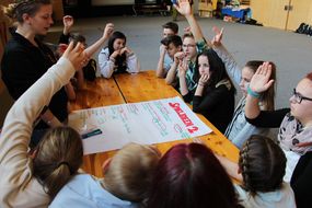 Kinder der Spielforscher-Werkstatt in der Europa-Mittelschule Prinzersdorf sitzen um einen Tisch und zeigen auf.
