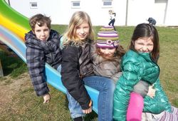 Kinder der schulischen Nachmittagsbetreuung spielen auf der Rutsche im Schulfreiraum.