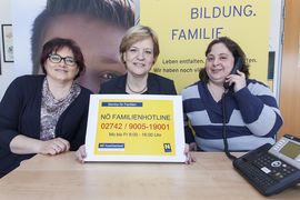 Landesrätin Schwarz zeigt ein Bild mit der Nummer der Familienhotline in die Kamera.
