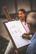 Ein Künstler zeichnet das Portrait einer Frau beim Sommerausklang an der Donau-Universtität Krems