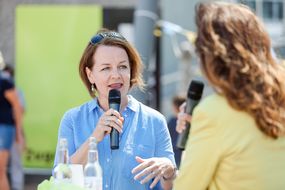 Zwei Damen sprechen beim Straßenfest zum Weltspieltag in das Mikrofon.