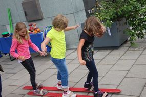 Drei Kinder versuchen zusammen mit zwei Skiern zu gehen 