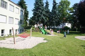 Kinder spielen bei strahlendem Sonnenschein am Schulfreiraum.
