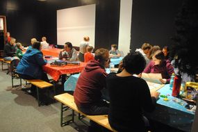 Familien sitzen an Tischen und spielen Brettspiele.