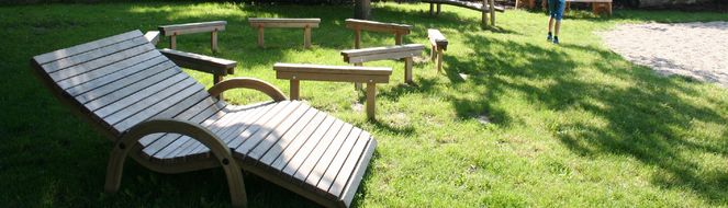 Hölzerne Sonnenstühle bei einem Spielplatz.