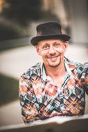 Mann mit Hut grinst in die Kamera