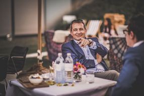 Mann mit Anzug lacht und zeigt in die Kamera