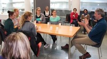 Seminarteilnehmerinnen sitzen um einen Tisch beim Cup-Song