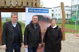Zwei Männer und eine Frau lachen vor einem NÖ Familienland-Roll-up stehend in die Kamera.
