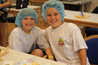 Zwei junge Buben mit blauen Haarnetzen lächeln auf der NÖ Kinder Business Week in die Kamera