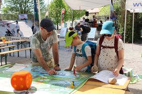Mann und zwei Kinder spielen ein Würfelspiel beim Familienfest Donau-Auen