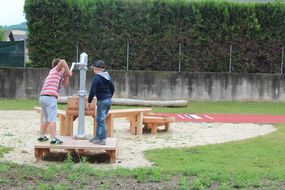Kinder pumpen beim Brunnen.
