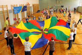 Kinder spielen mit einem bunten Schwungtuch im Turnsaal