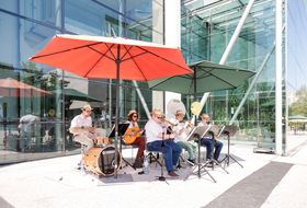 Eine sechsköpfige Band spielt unter Sonnenschirmen am Straßenfest zum Weltspieltag