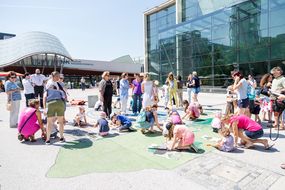 Kinder und Eltern sitzen am Boden und füllen Zettel aus